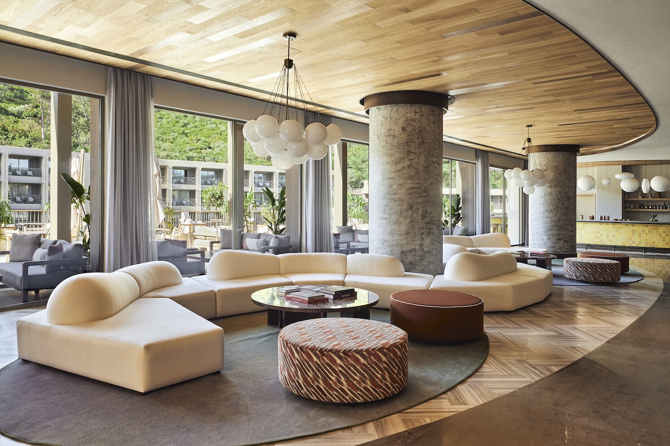 Lobby image with cream endless sofa, patterned ottoman, and round bulbed chandelier